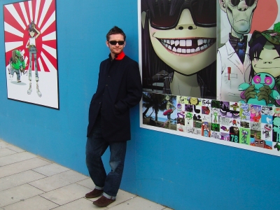 Jamie Hewlett poses with his artwork outside the F